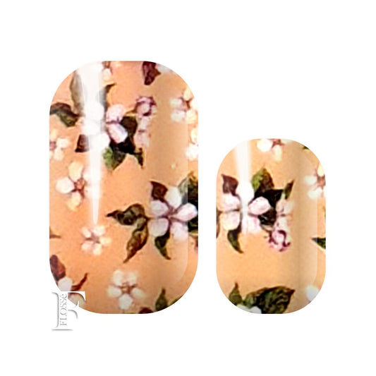 nail wraps with a soft peachy pink base covered in white blossom flowers