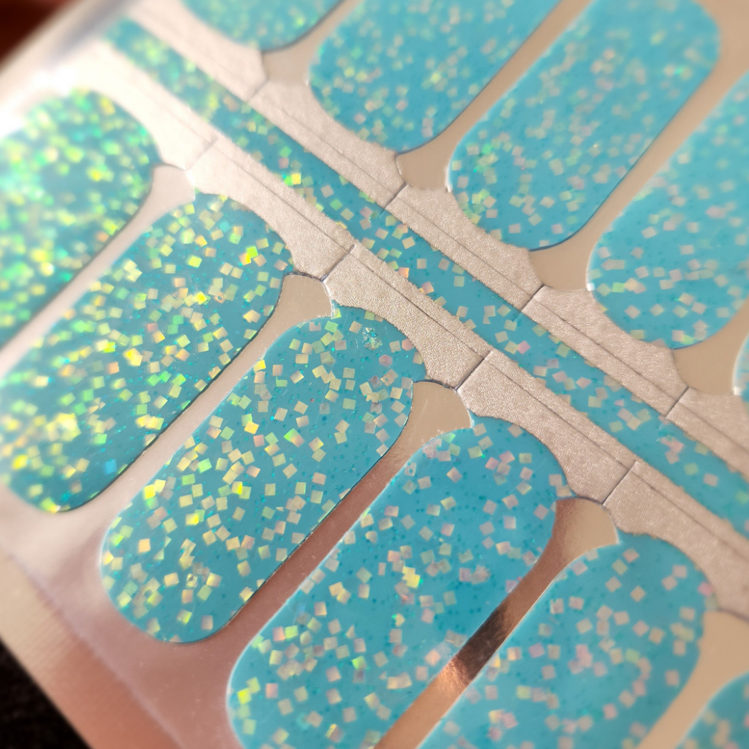 Close up of FLOSSé Topaz nail wraps showing bright teal aqua blue base with golden luminescent sequins.